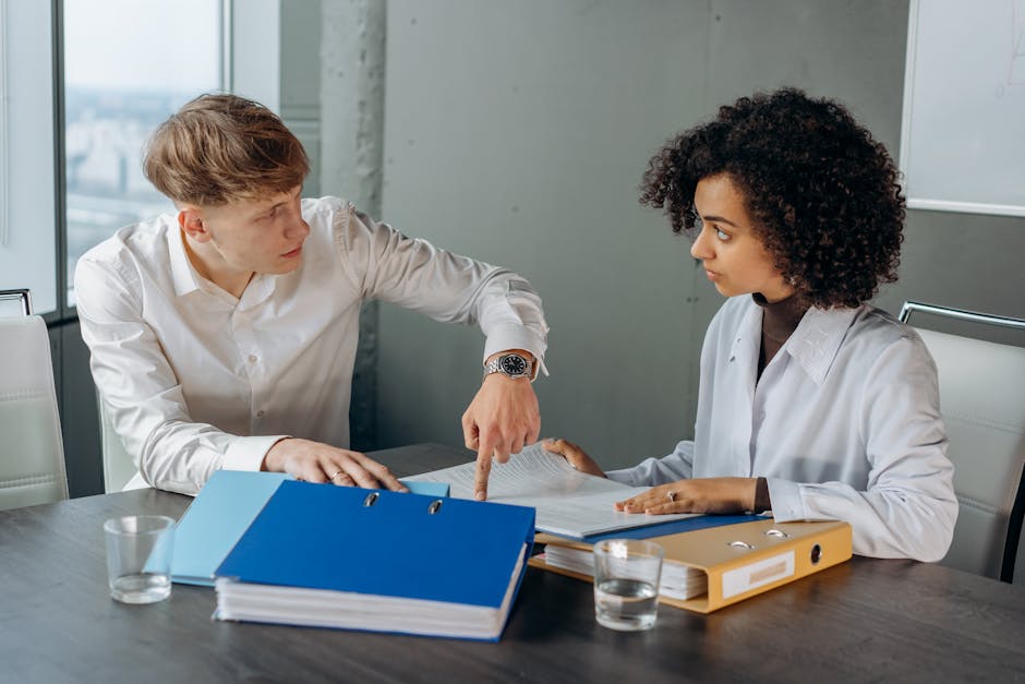 Professional workplace discussion between colleagues reviewing documents at an office table.